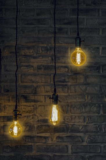 Vintage edison light bulbs on wire with brick wall on background