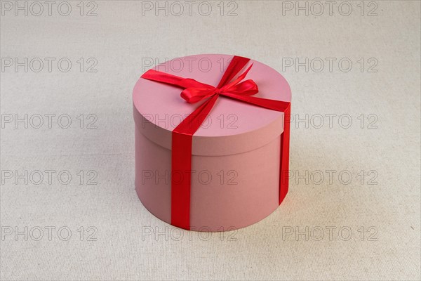 Round pink giftbox with red ribbon