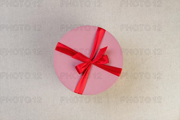 Round pink giftbox with red ribbon