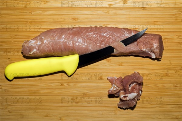 Pork fillet is freed from the silver skin with a knife