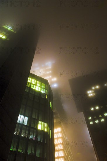 Illuminated skyscrapers in the fog at night