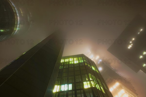 Illuminated skyscrapers in the fog at night