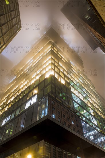 Illuminated skyscrapers in the fog at night