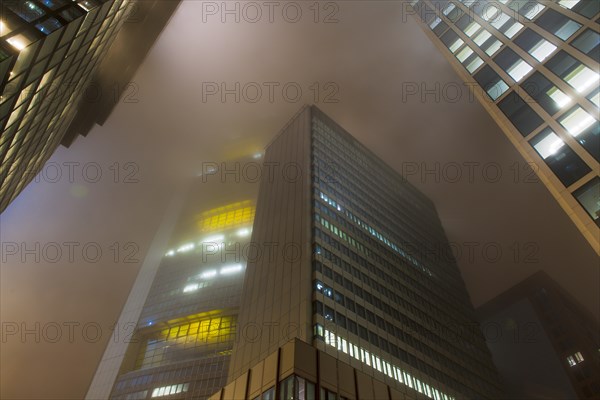 Illuminated skyscrapers in the fog at night