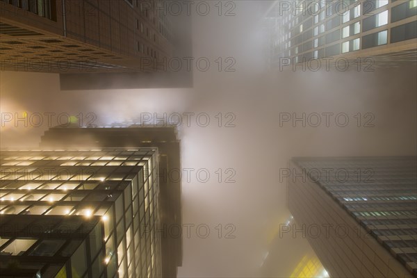 Illuminated skyscrapers in the fog at night