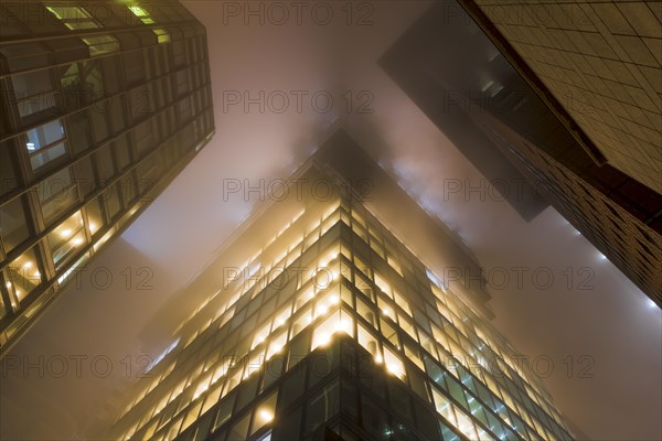 Illuminated skyscrapers in the fog at night