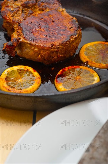 Pork chop seared on iron skillet with lemon and spices seasoning