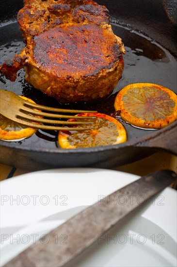 Pork chop seared on iron skillet with lemon and spices seasoning