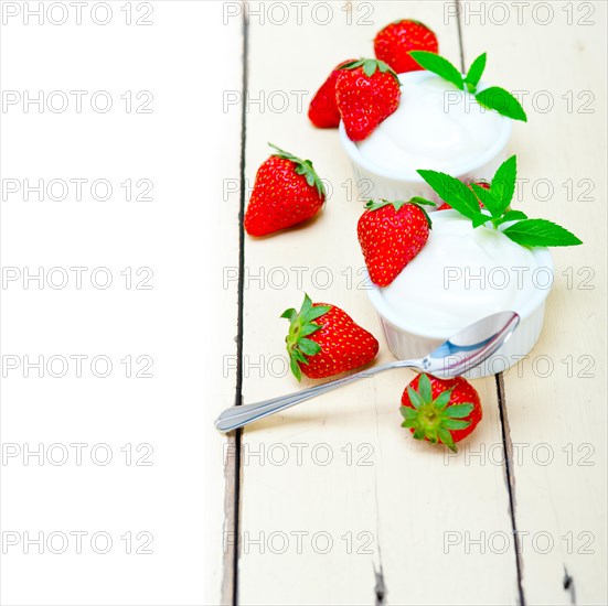 Organic Greek yogurt and strawberry over white rustic wood table