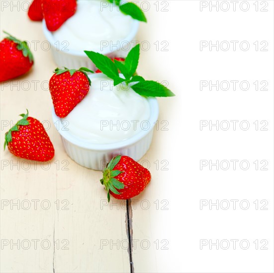 Organic Greek yogurt and strawberry over white rustic wood table