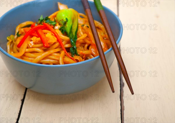 Hand pulled stretched Chinese ramen noodles on a bowl with chopstick