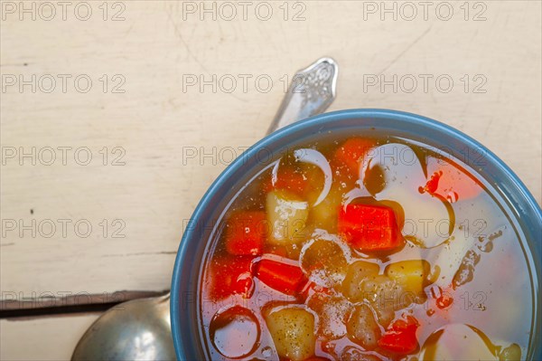 Traditional Italian minestrone soup on a rustic table with ingredients