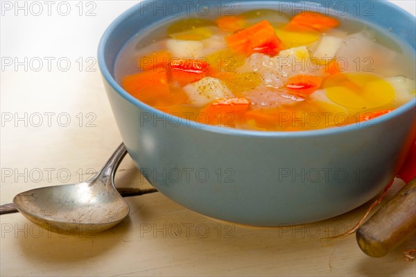 Traditional Italian minestrone soup on a rustic table with ingredients