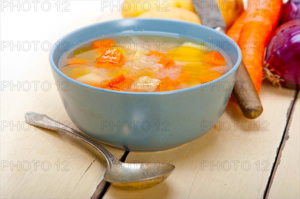 Traditional Italian minestrone soup on a rustic table with ingredients