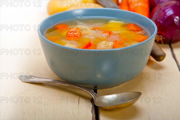 Traditional Italian minestrone soup on a rustic table with ingredients