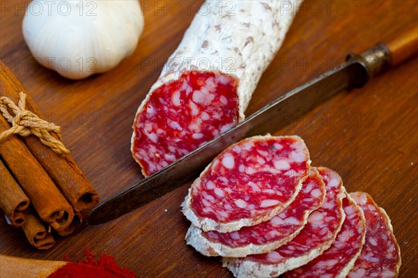 Traditional Italian salame cured sausage sliced on a wood board
