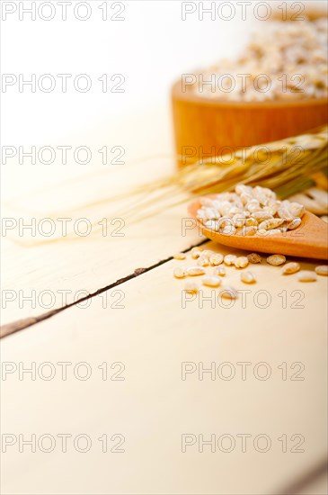 Organic barley grains over rustic wood table macro closeup