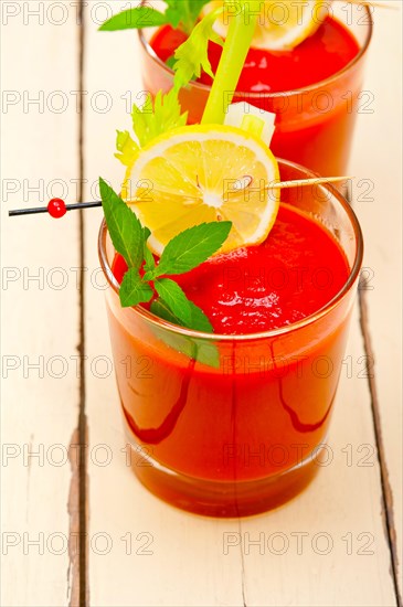 Fresh tomato juice gazpacho soup on a glass over white wood table