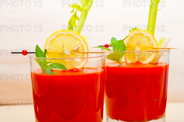 Fresh tomato juice gazpacho soup on a glass over white wood table