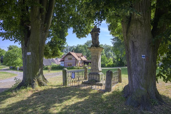 Sculpture of the Holy Trinity and old wooden house