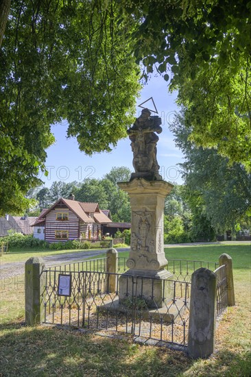 Sculpture of the Holy Trinity and old wooden house