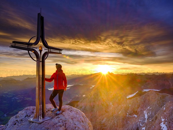 Mountaineer at the summit cross Hohe Goell at sunrise