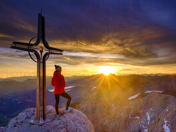 Mountaineer at the summit cross Hohe Goell at sunrise