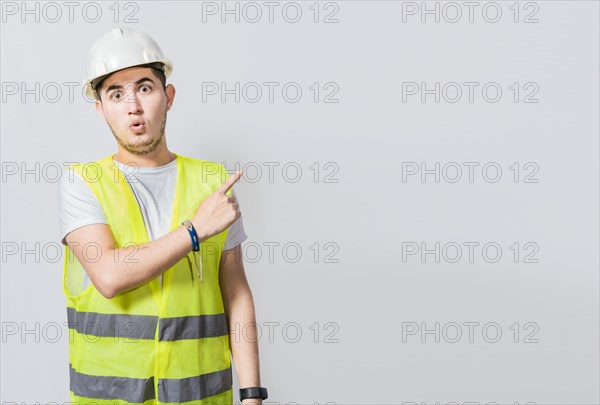 Surprised face construction worker pointing at an advertisement. Engineer man pointing to side. Surprised face engineer pointing finger to the right