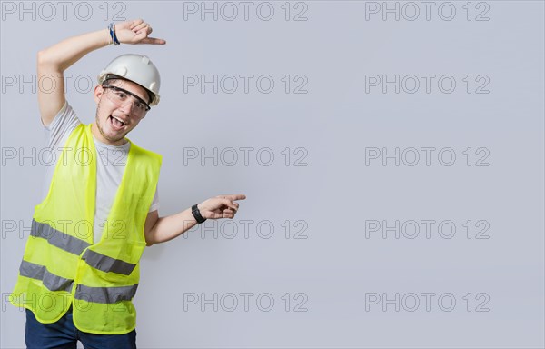 Construction engineer with vest pointing at an advertisement. Engineer man pointing to side. Smiling engineer man pointing aside