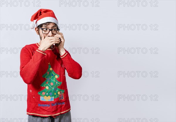Man in christmas hat talking on the phone secretly. Christmas guy talking on the phone secretly