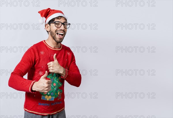 Happy young man in christmas hat giving thumbs up. People in santa hat doing ok gesture. Concept of christmas man giving thumbs up