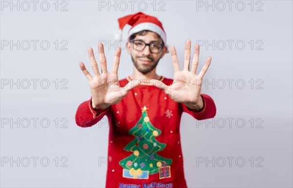 Man in christmas hat counting number ten with fingers. Christmas young man counting number ten with hands. Concept of man in christmas costume counting number ten isolated