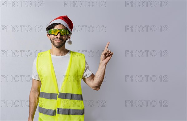 Builder worker with christmas hat pointing a finger at a promotion. Builder engineer in christmas hat pointing to the right