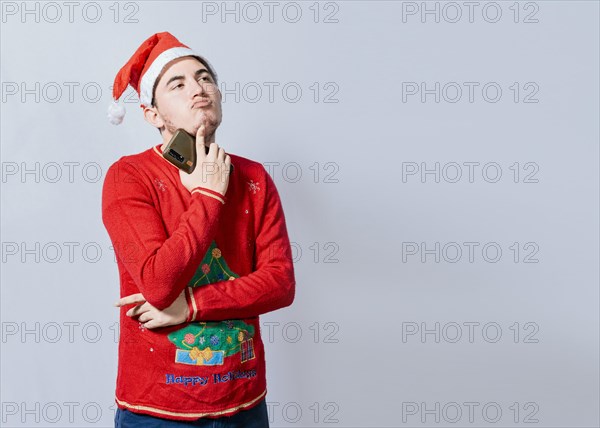 Thoughtful man with christmas hat holding cell phone