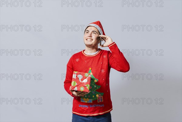 Happy guy holding gift and calling family at christmas