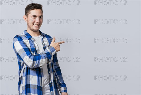 Smiling handsome man recommending something with his fingers. Caucasian handsome guy pointing his finger at a blank space