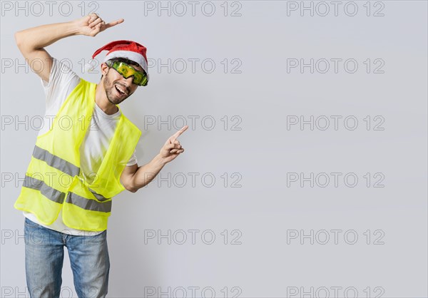 Builder worker with christmas hat pointing a christmas promotion. Builder engineer in christmas hat pointing a copy space. Engineer man in christmas hat showing a product