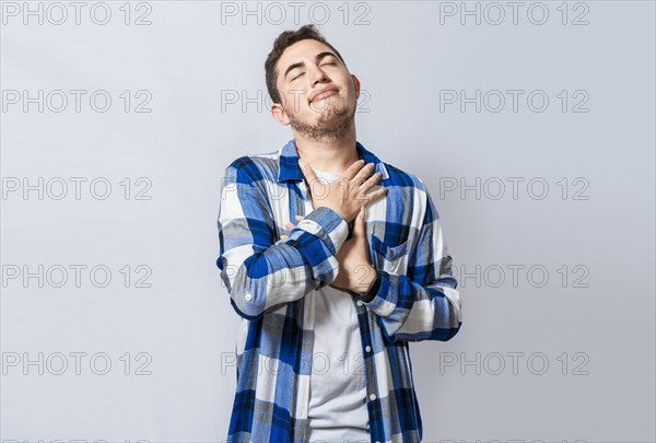 Grateful young guy smiling with hands on chest