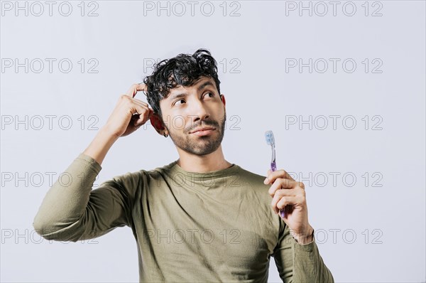Thoughtful man holding toothbrush isolated