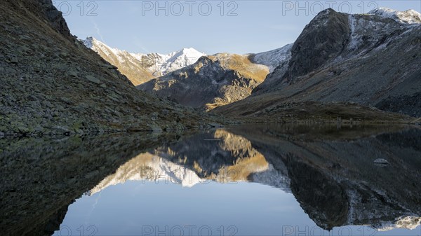 Slightly snow-covered mountains reflected in Schwarzsee in autumn on the Flueela Pass