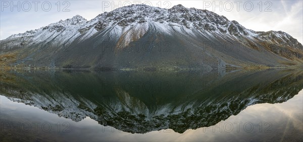 Slightly snow-covered mountains reflected in Lake Schotten in autumn at the Flueela Pass