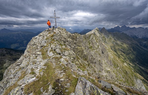 Hiker on the summit of the Raudenspitze with summit cross