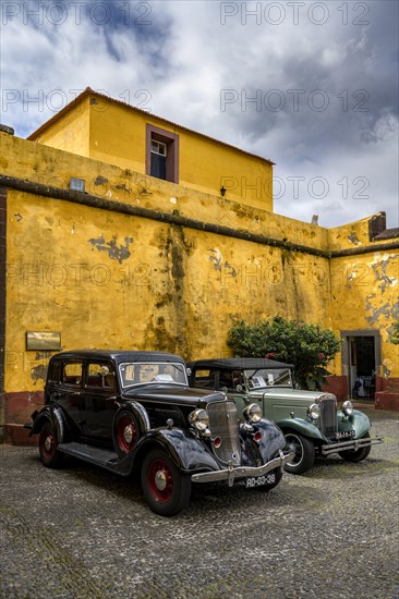 Vintage cars parked in front of yellow wall