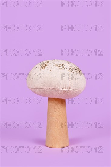 Autumn mushroom decoration made out of wood and cloth on violet background