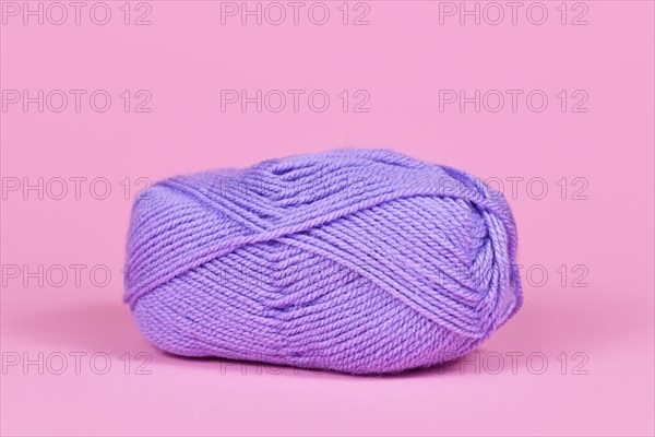 Single violet ball of wool on pink background