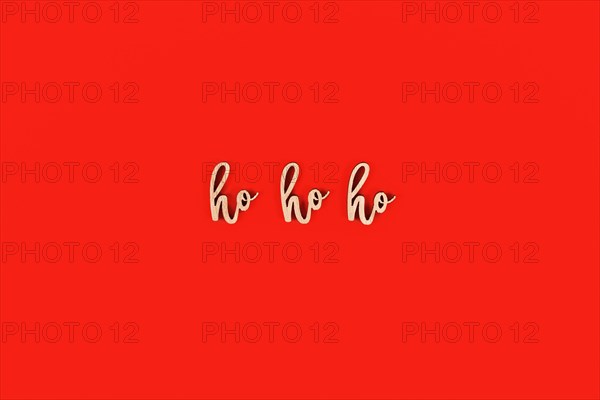 Seasonal Christmas wooden letters forming words 'ho ho ho' on red background
