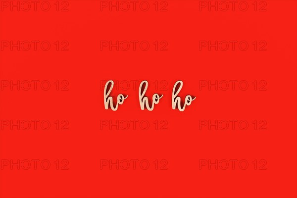 Seasonal Christmas wooden letters forming words 'ho ho ho' on red background