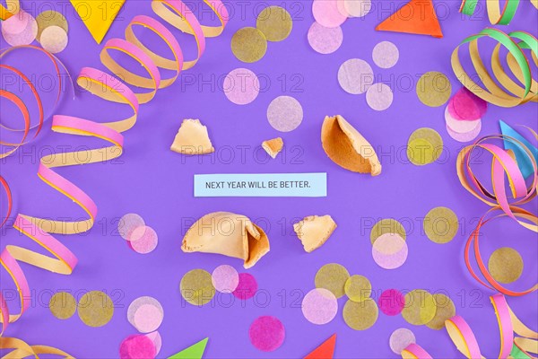 Motivational New Year celebration concept with open fortune cookie and text Next year will be great on colorful background with paper streamers and confetti