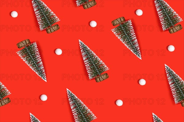 Small Christmas trees and snowballs flat lay on bright red background