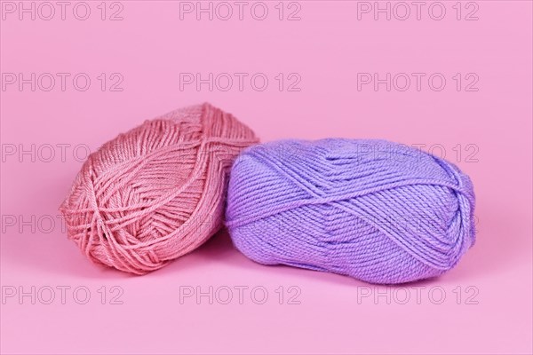 Two balls of wool on pink background